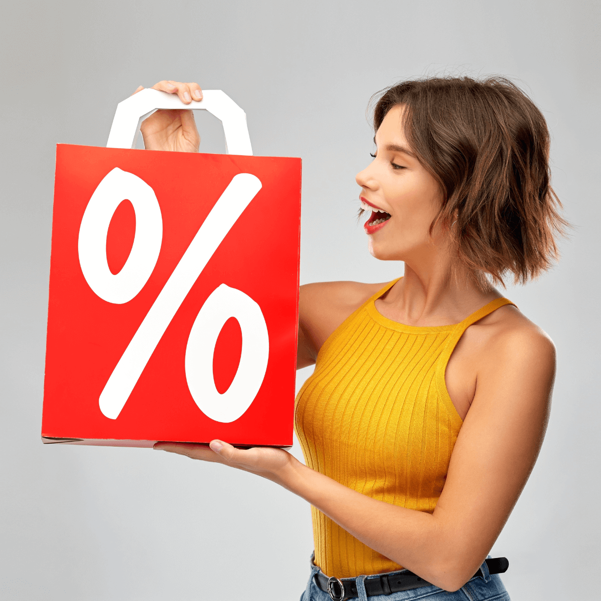 Eine Frau hält eine rote Papiertüte in die Höhe. Auf der Tüte ist ein Prozentzeichen zu sehen.