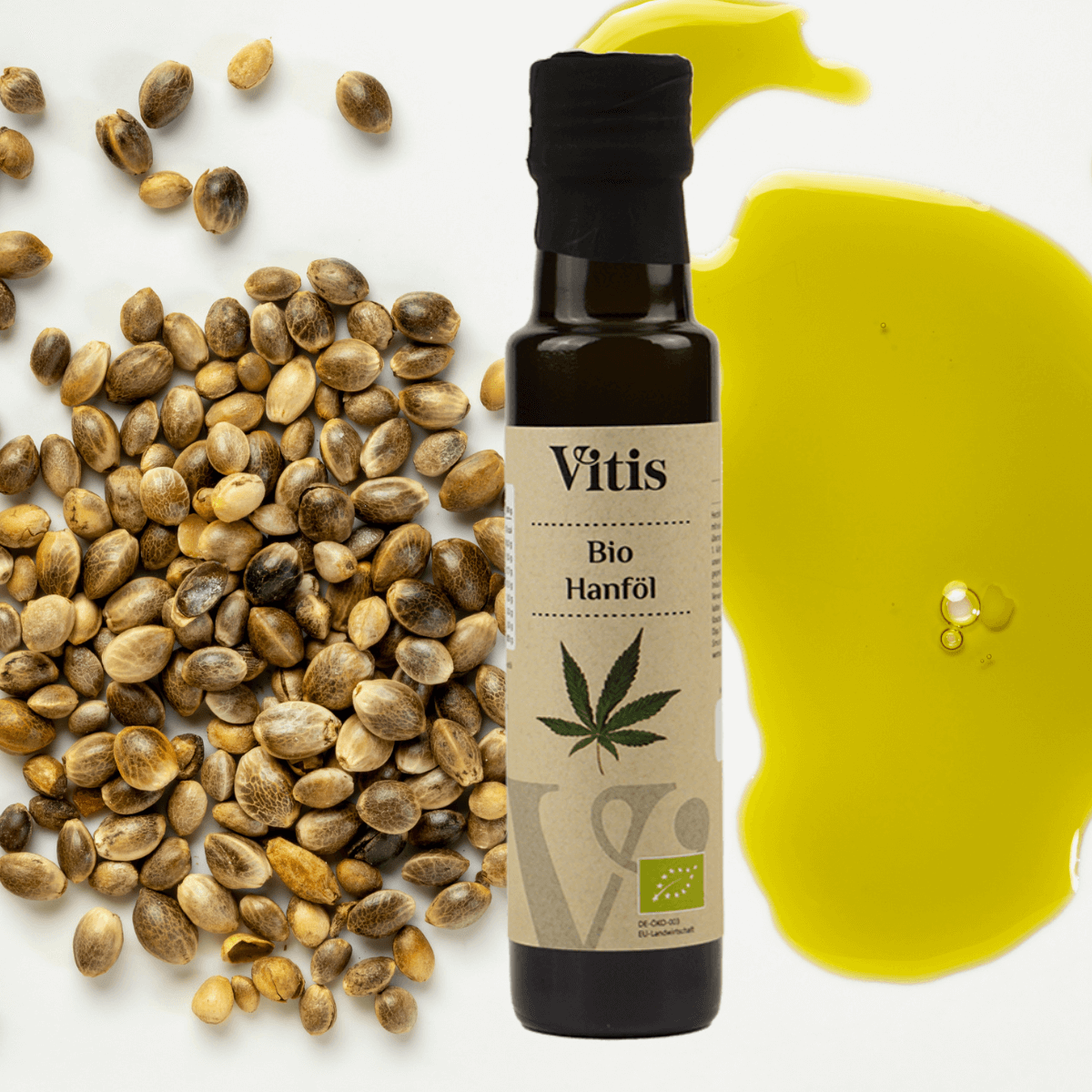 Eine Flasche Bio Hanföl von Vitis mit Hanfsamen im Hintergrund.