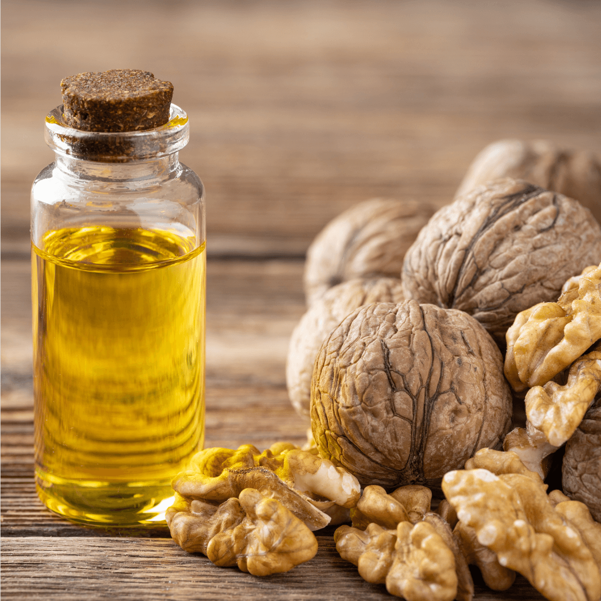 Eine kleine Flasche Walnussöl auf einem Holztisch. Daneben liegen Walnüsse.