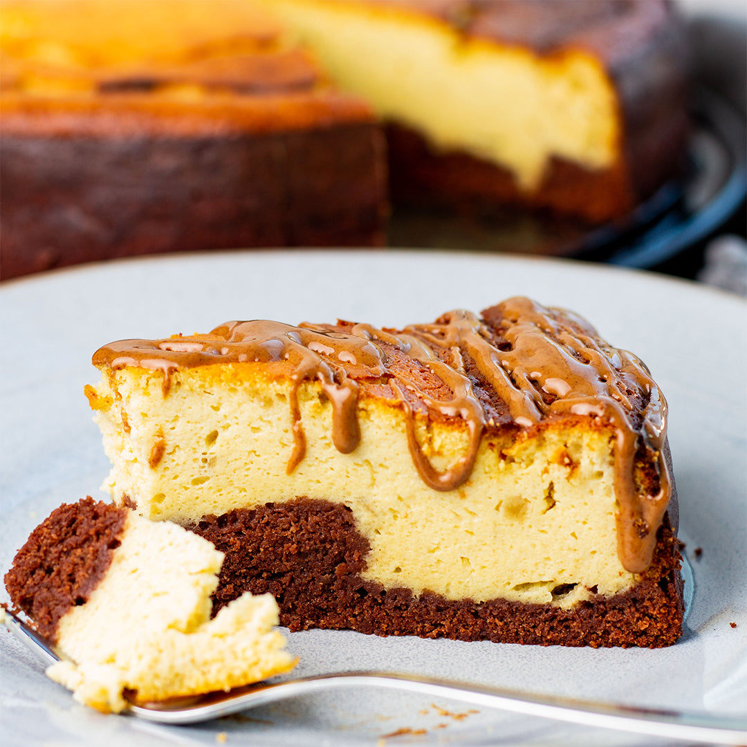 Ein Teller mit einem Stück Käsekuchen und einem Silberlöffel.