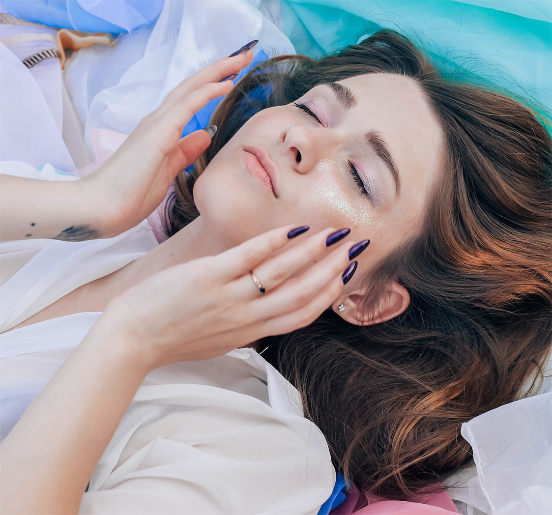 Oberkörper einer liegenden Frau um die 35 Jahre, die sich Traubenkernöl auf Ihre Wangen reibt