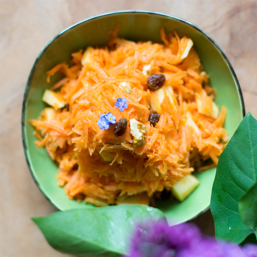 eine grüne Schale Salat aus geriebenem Apfel und geriebener Karotte