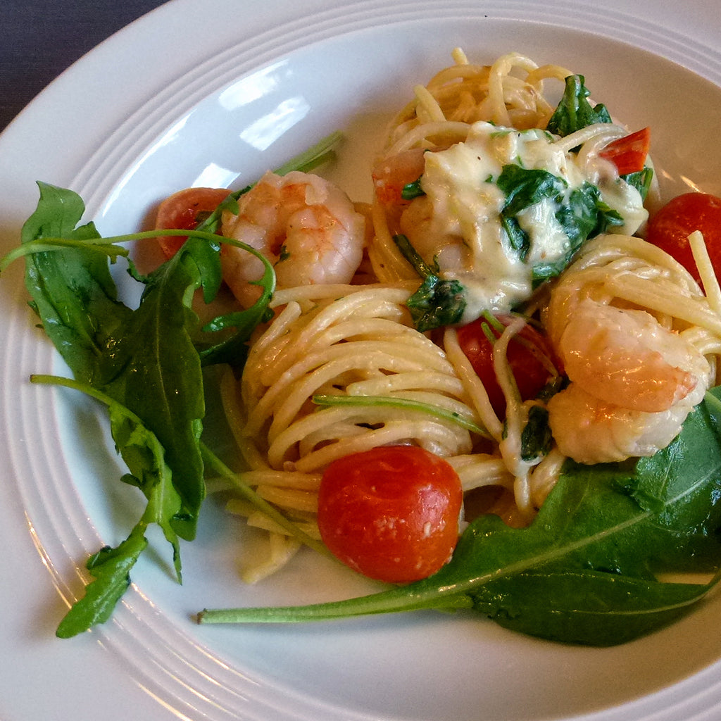 ein Teller mit Spaghetti, Garnelen, Kirschtomaten und einer pikanten Mozzarellasauce