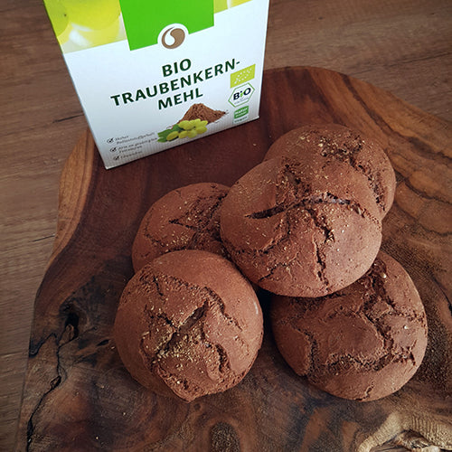 Frisch gebackene Traubenkernbrötchen mit einer Packung 250 Gramm Bio Traubenkernmehl von Vitis im Hintergrund.