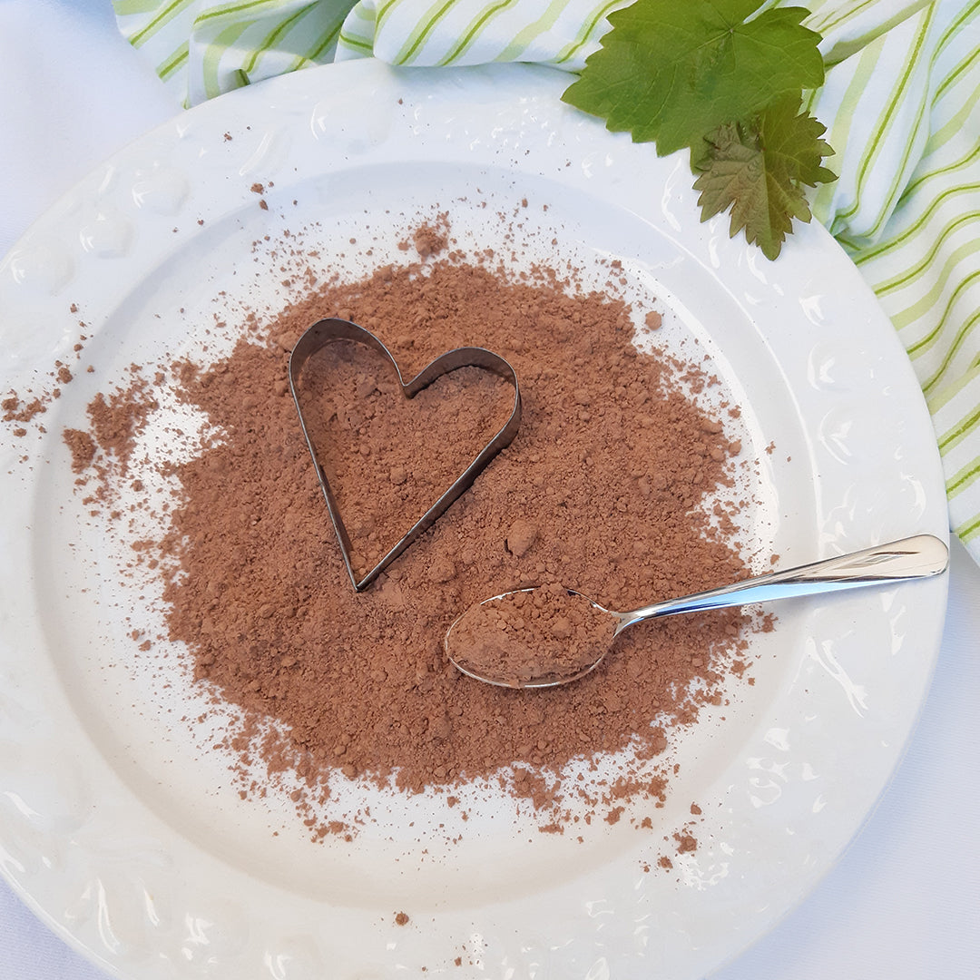 ein weißer Teller mit Traubenkernmehl, einer Herz-Ausstechform und einem silbernen Teelöffel