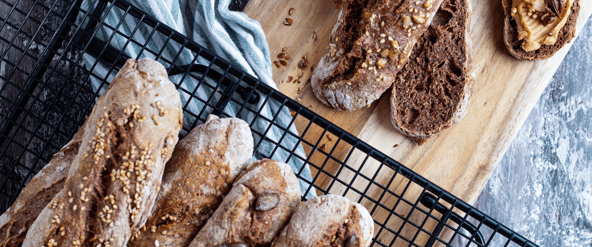 Traubenkernbrot und Traubenkernbaguette dekorativ angerichtet auf einem Holzbrett.