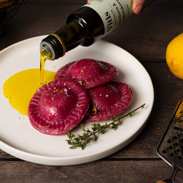 Raps- & Traubenkernöl Zitrone wird auf einen Teller mit rote Bete Ravioli gegossen.